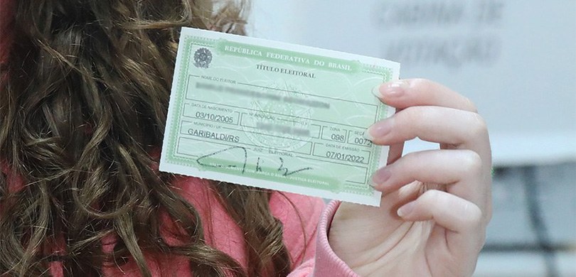 Justiça Eleitoral bate recordes de atendimentos no dia do fechamento do cadastro eleitoral Fotografia mostrando uma pessoa segurando seu título de eleitor